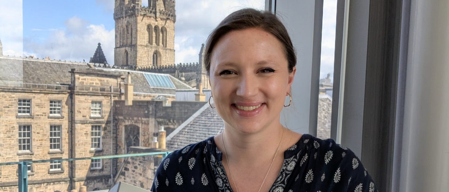 Dr Maya Feile Tomes smiles and holds out an original C17th copy of 