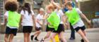 Children running around cones in a school playground. Some children are wearing hi-vis vests.