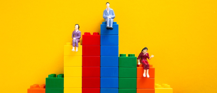People miniatures sitting on building blocks