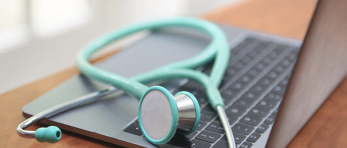 A green stethoscope sits on top of a laptop