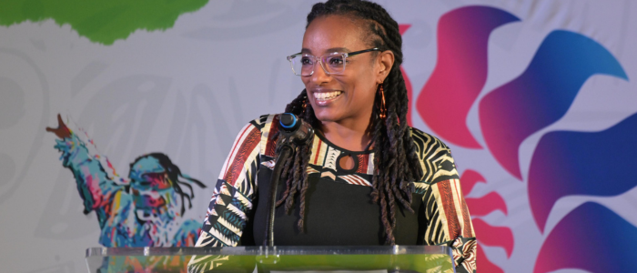 A woman standing at a podium with a microphone smiling