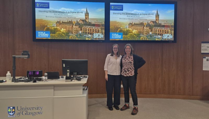 Professor Nicola Veitch stood side by side with Sii Director of Education Professor Olwyn Byron after delivering her inaugural lecture. The pair are stood in the wood-panelled lecture theatre to the left left of the lectern and below the double screen mounted on the wall.