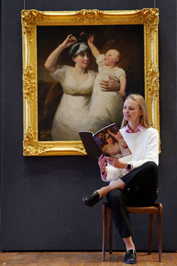 Woman in a white shirt sitting in front of a painting of a woman and child.