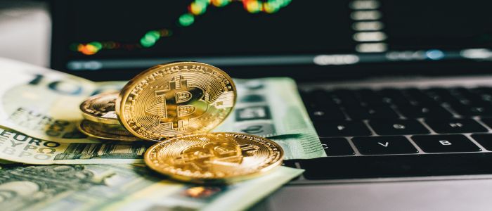 Gold coins and bank notes sitting on a laptop keyboard