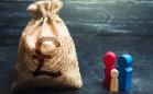 Bag of money next to wooden figures depicting a family