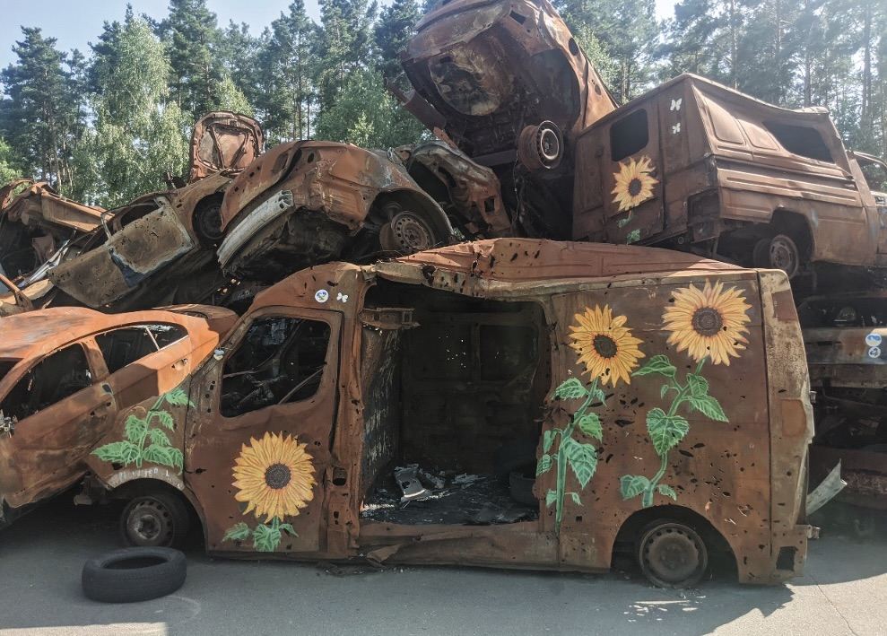 ‘car graveyard’ in Irpin, Ukraine. A stack of burned and rusted vehicles adorned with sunflower artwork. Photo by Alisa Demina (see link to JCA paper) ‘car graveyard’ in Irpin, Ukraine. A stack of burned and rusted vehicles adorned with sunflower artwork. Photo by Alisa Demina (see link to JCA paper)