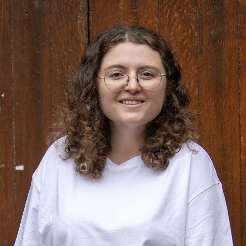 photo of Steph a white person, with brown curly hair who wearing a white t-shirt.