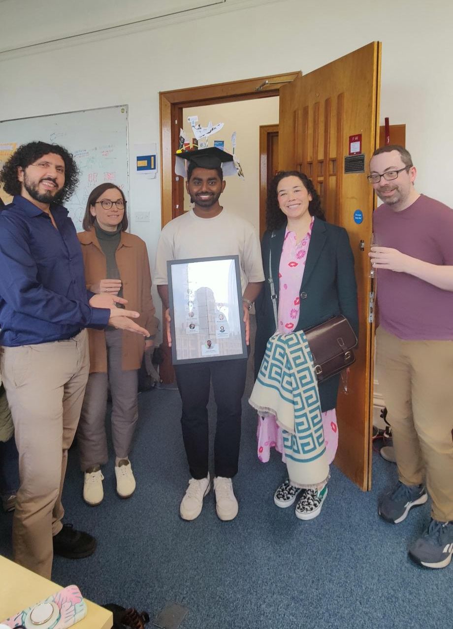 Five people looking at the camera. One is holding a picture frame.