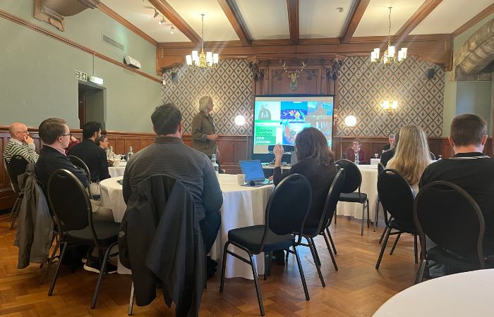 A group of people sitting in a room with one person presenting