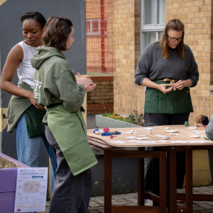 Three members of staff standing around a table where a creative activity with clay is taking place.