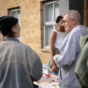 Two people photographed from behind standing next to a table with pieces of colourful clay sitting on it.