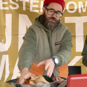 A member of staff weighing a brown paper bag full of produce on the scales.