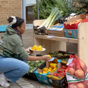 A member of staff crouching down next to the boxes of fruit and reaching to pick something up.