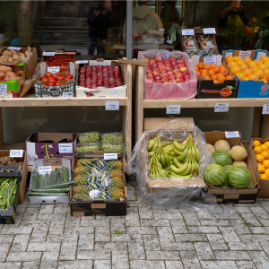 Boxes of fruit and veg set up on shelves. The display looks very colourful and fresh.