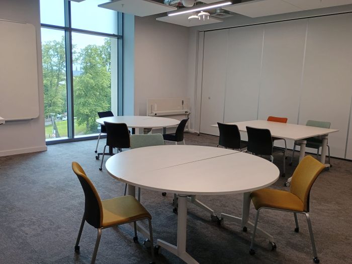 Flat floored teaching room with tables and chairs, and whiteboard.