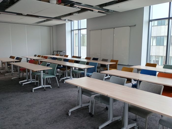 Flat floored teaching room with tables and chairs, and whiteboard.