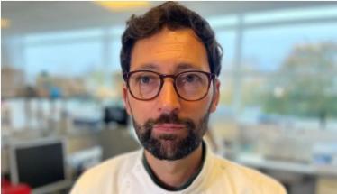 Close up head shot image of Daniel Streicker in a lab wearing a lab coat