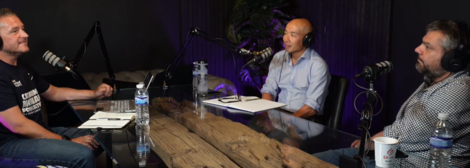 An image of podcast host Derek McEwan and experts Gwo-tzer Ho and Konstantinos Gerasimidis sat in the studio with mics and a large wooden desk. Derek is sat to the left, with Gwo-tzer and Konstantinos on the right, facing Derek.