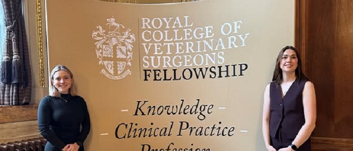 Aine O'Brien and Rylyn Koger standing in front of the RCVS Fellowship Day Banner