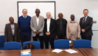 Delegates (Professor Adamu Ahmed; Professor YKE Ibrahim; Professor Iliya S. Ndams, Professor Emmanuel Balogun, Harry de Koning; Andy Schofield, Iain McInnes) stood together in a room in front of a white board and behind a conference table.