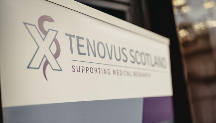 The Tenovus Scotland logo on a plaque that is pictured at an angle