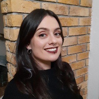 smiling dark-haired female staff member with a brick wall background
