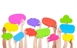 Several raised hands holding colorful speech bubbles in various shapes, including circles, rectangles, and clouds. The bubbles are in bright colors such as pink, purple, blue, green, yellow, and orange, set against a plain white background, symbolizing communication, ideas, and diversity of voices.