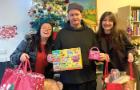 Three people holding up bags with presents