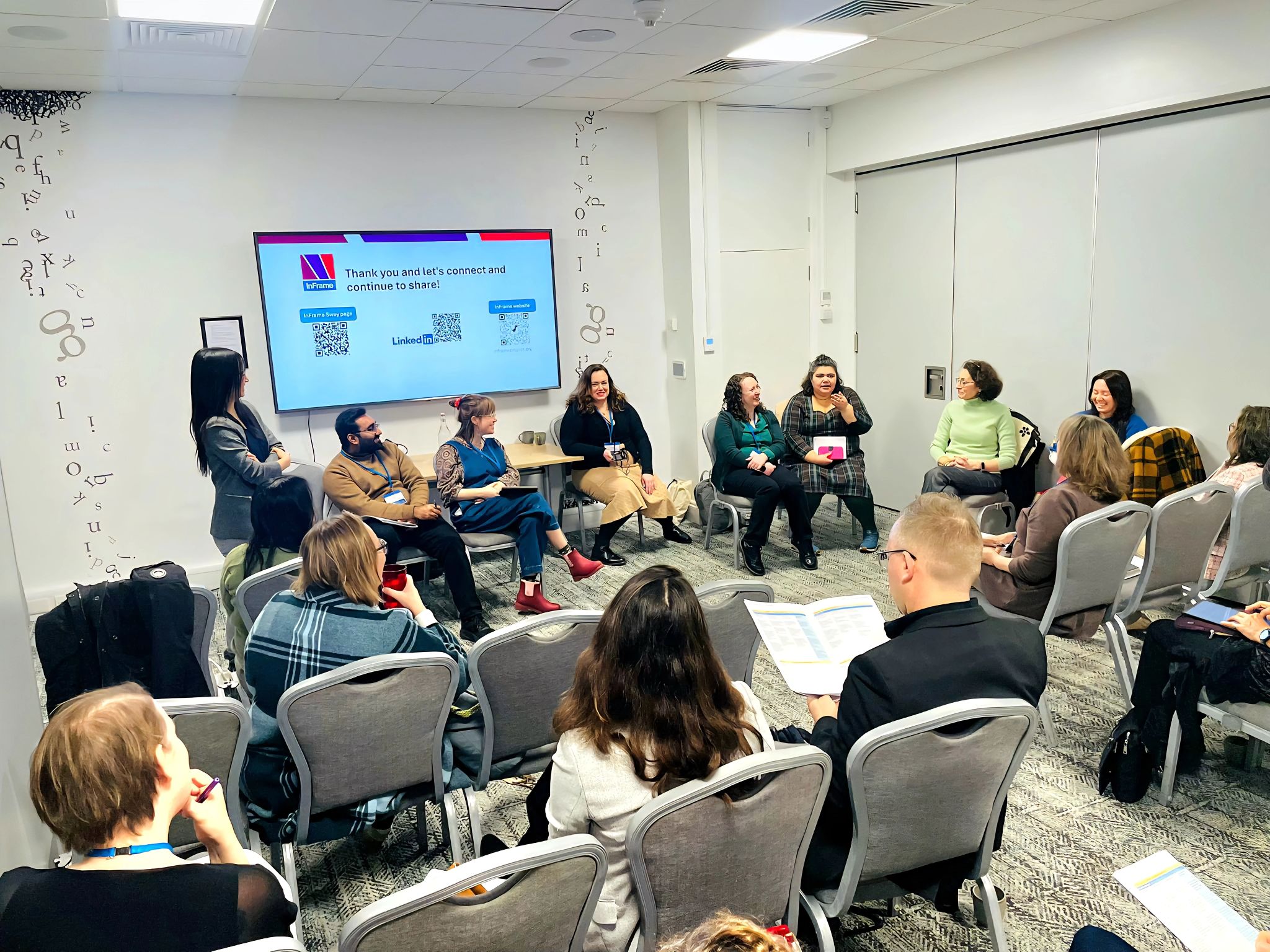 Round‑table discussion session at an SRHE conference, with InFrame team members and participants seated in a circle and engaging in conversation. A presentation screen in the background displays closing slides and information for staying connected, reflecting collaborative dialogue and shared learning around research culture and collegiality.