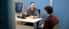 A student and staff member sitting at a desk having a conversation.