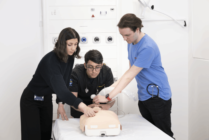 Medical students practising assessment of patient on a mannequin