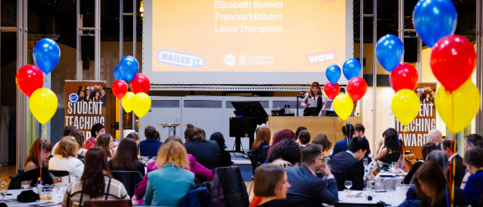 A photo of the Student Teaching Awards Ceremony with people sitting at tables, multi-coloured balloons and a stage.