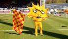 Partick thistle mascot Kingsley (a yellow sun-like figure) stands on the grounds of Firhill stadium