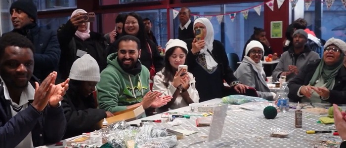 Group of people sitting around the big table in Byres Hub. Some are holding mobile phones and smiling to each other