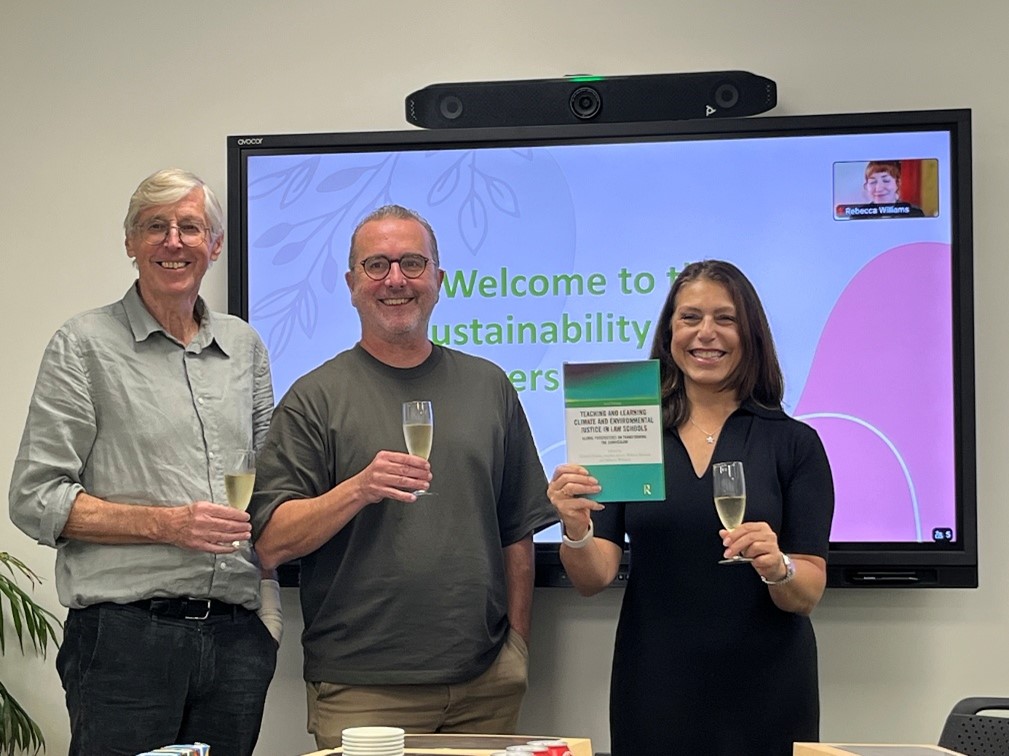 Three people holding up a book at a function