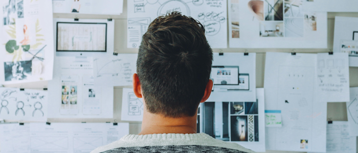 A man thinking in front of a wall of notes