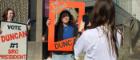 A student posing for a photo with a banner around her saying