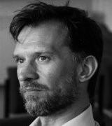 A head and shoulders portrait shot of Professor Carl Goodyear. Carl is in a slight side profile and the image is black and white.