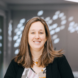 A headshot of a smiling woman with shoulder-length brown hair