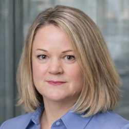 A headshot of a smiling woman with shoulder-length blonde hair