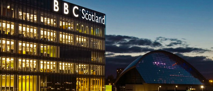 The BBC Scotland Headquarters Building in Glasgow. With the illuminated BBC sign and lights emanating from the building at dusk.