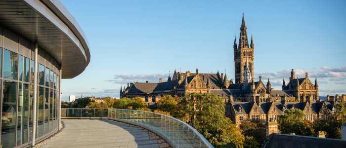 The JMS balcony in the foreground, overlooking a tree-filled landscape in autumn colours. In the background stands the Gilbert Scott Tower.