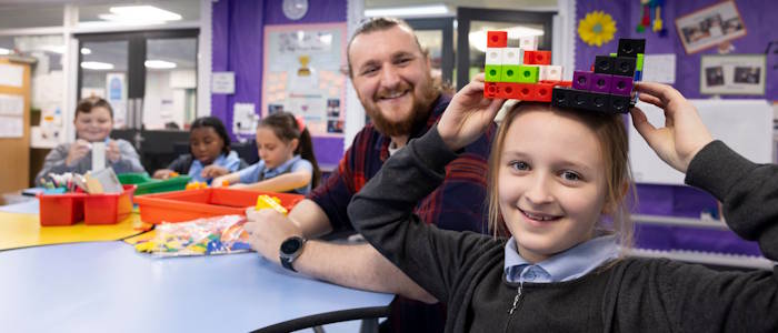 man and school child playing with lego