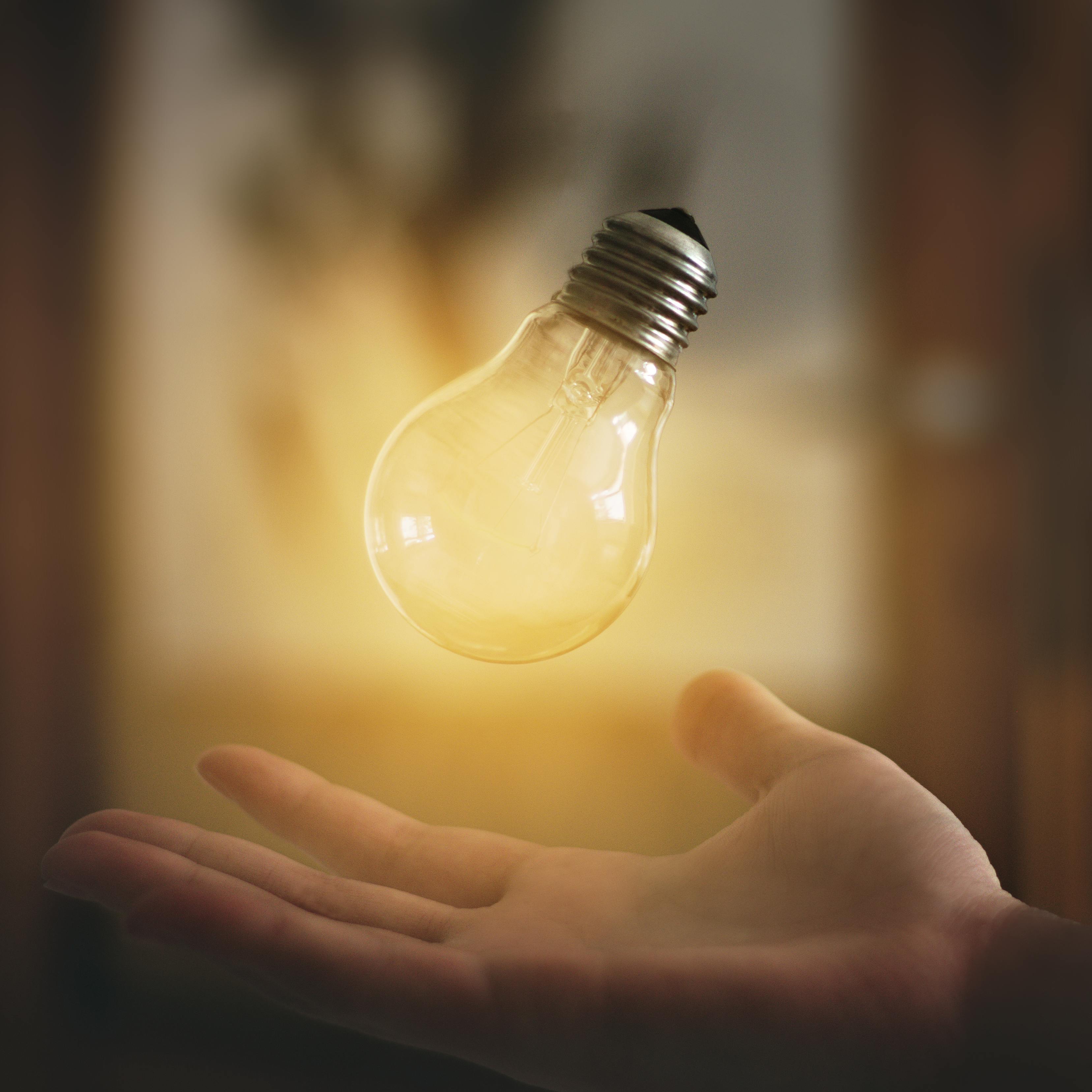 A glowing lightbulb floating above an open hand, symbolising ideas and inspiration.