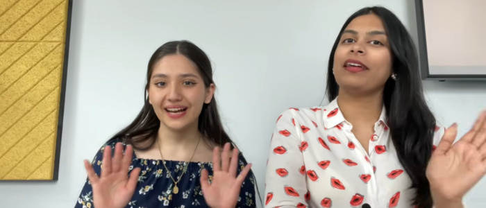 Two students waving at the camera with the caption 
