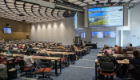 Delegates attend a presentation during the British Society for Parasitology (BSP) 2026 Spring Meeting in the James McCune Smith Learning Hub at the University of Glasgow, with researchers seated across a large lecture theatre facing multiple presentation screens