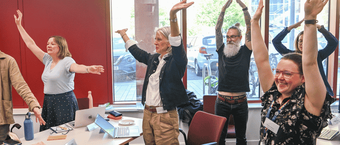 A group of people raising their hands in the air and smiling