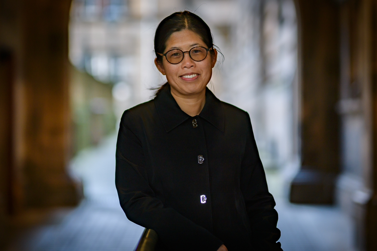 Smiling woman in a black jacket with black hair and glasses
