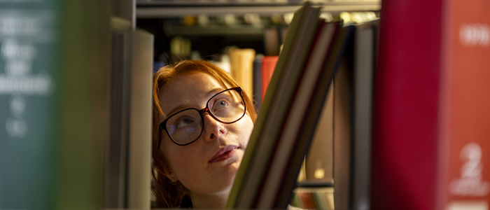 A student looks at books on a library shelf