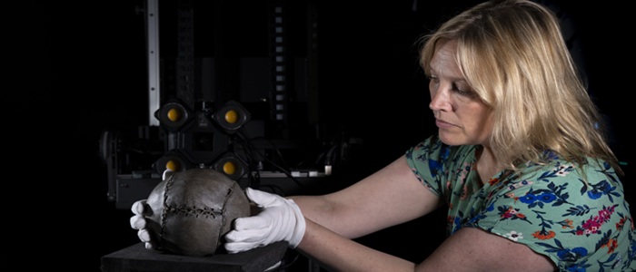 A woman wearing white gloves holds the world oldest football on a virutal reality 3D scanner. Credit Martin Shields